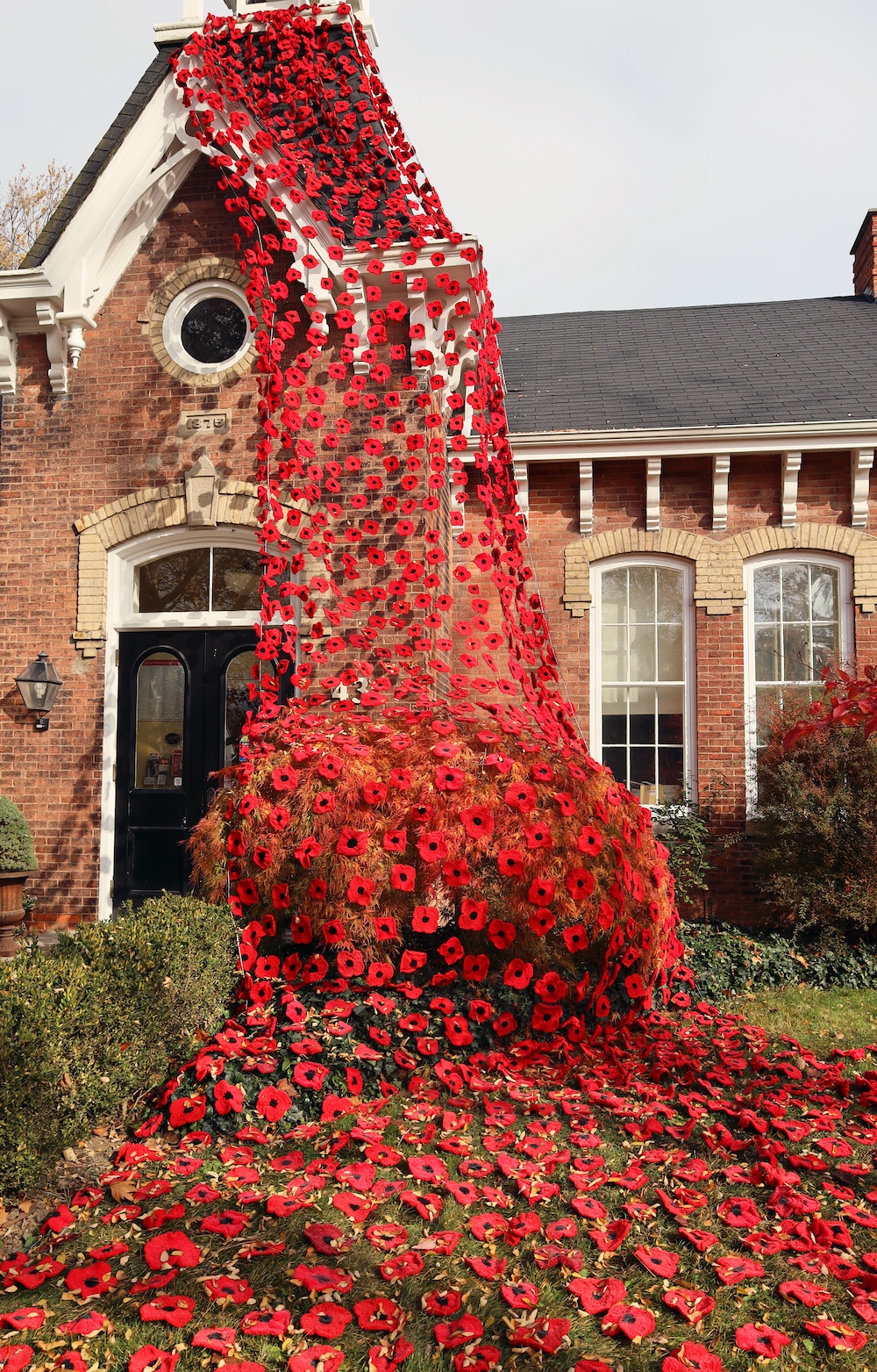 Brick building topped by a bell tower draped with poppies.