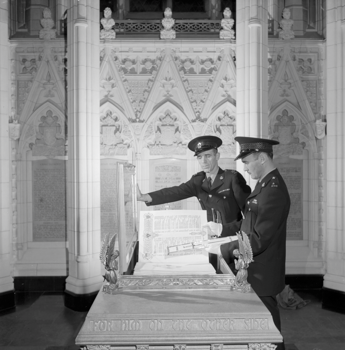 2 uniformed soldiers inspect an encased manuscript in front of gothic architectural motifs.